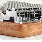 Side detail of the kalimba metal bridge, layered tines and rounded Okoume wood body