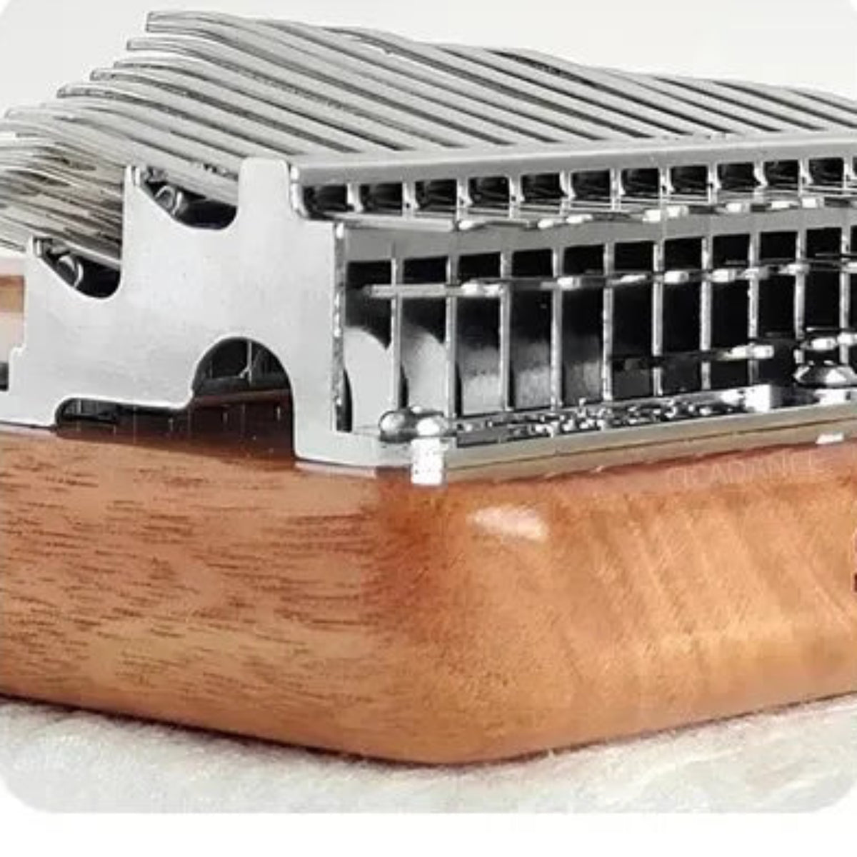 Side detail of the kalimba metal bridge, layered tines and rounded Okoume wood body