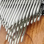 Close-up of the kalimba metal tines and engraved musical notes over the Okoume wood body