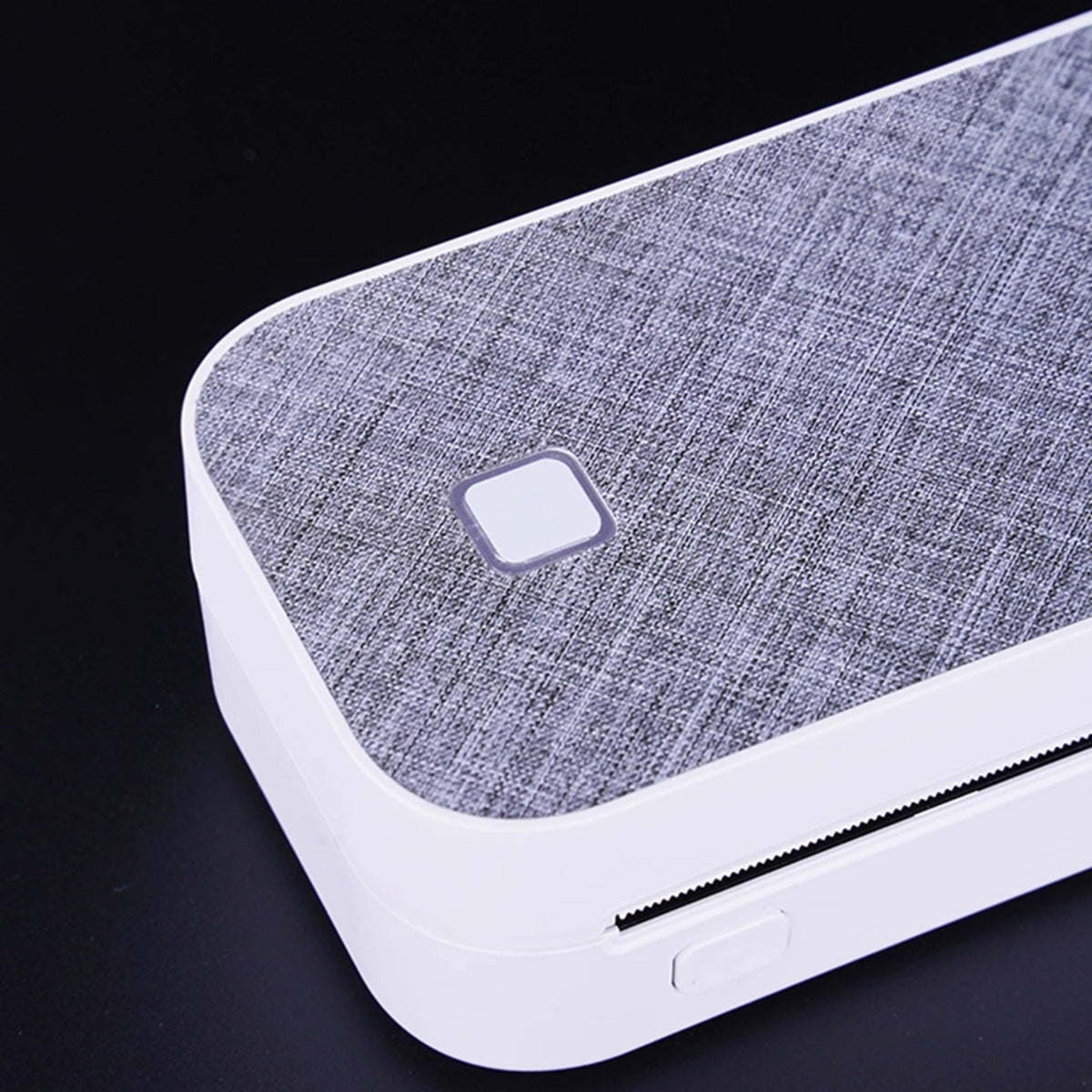 Close-up of the textured printer top, square control button and front paper-feed opening.