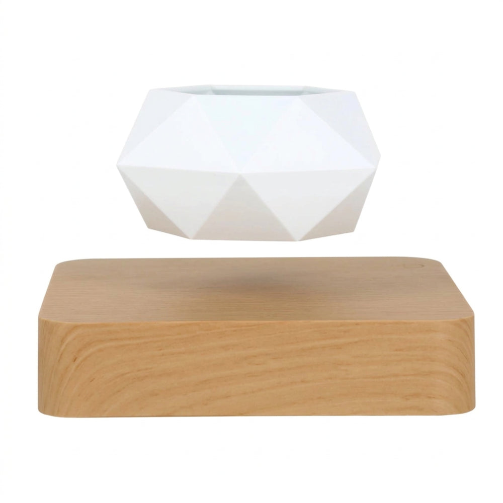 Empty white geometric planter suspended above its light wood-effect square magnetic base on a white background
