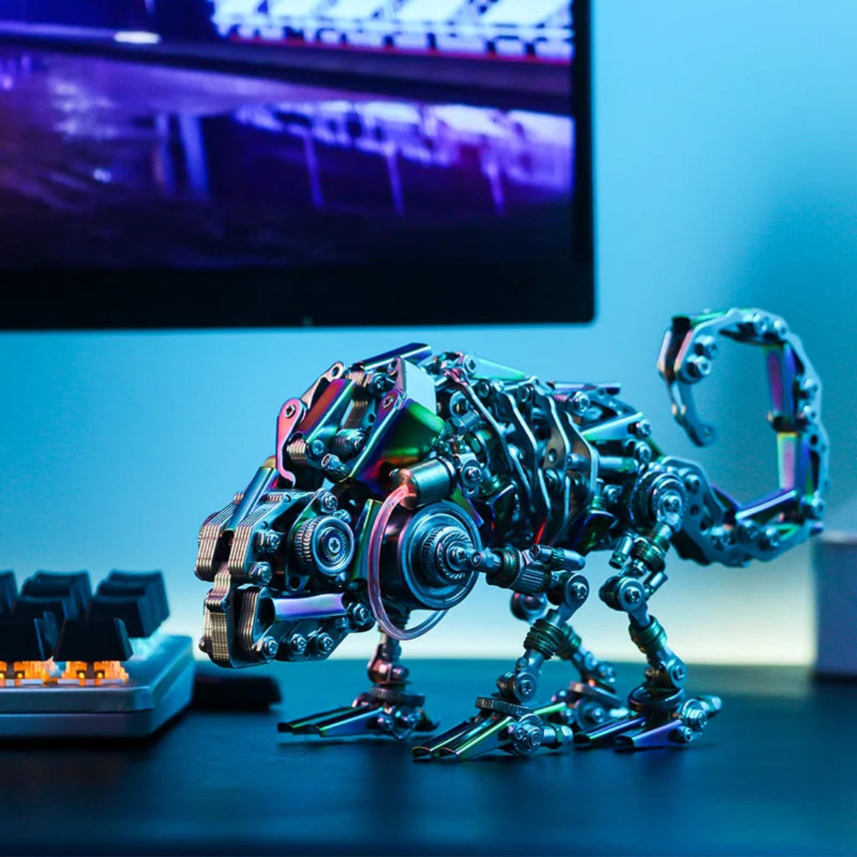 Assembled mechanical chameleon metal model with curled tail displayed beside a computer keyboard
