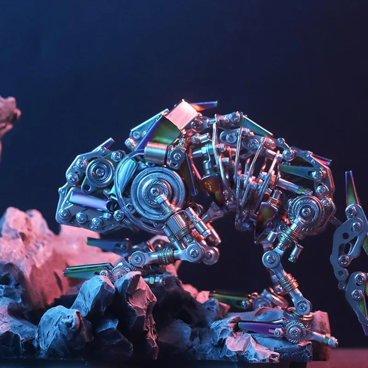 Side view of the assembled mechanical chameleon metal sculpture posed on rocks; scenery is for illustration