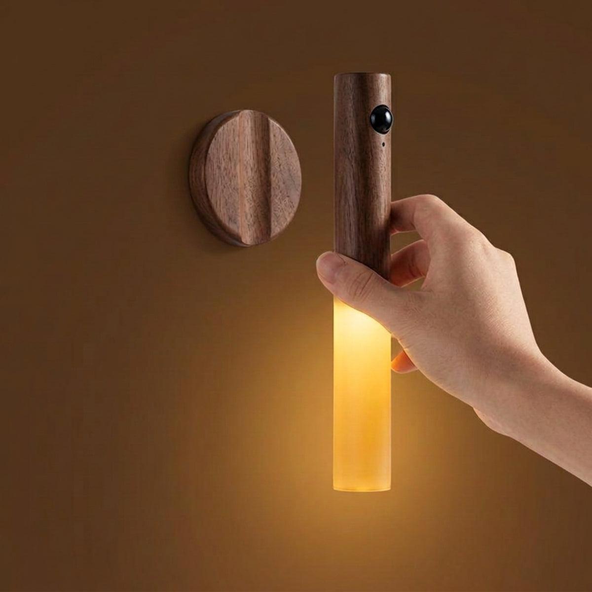 Hand lifting the rechargeable wall light away from its round magnetic mounting base