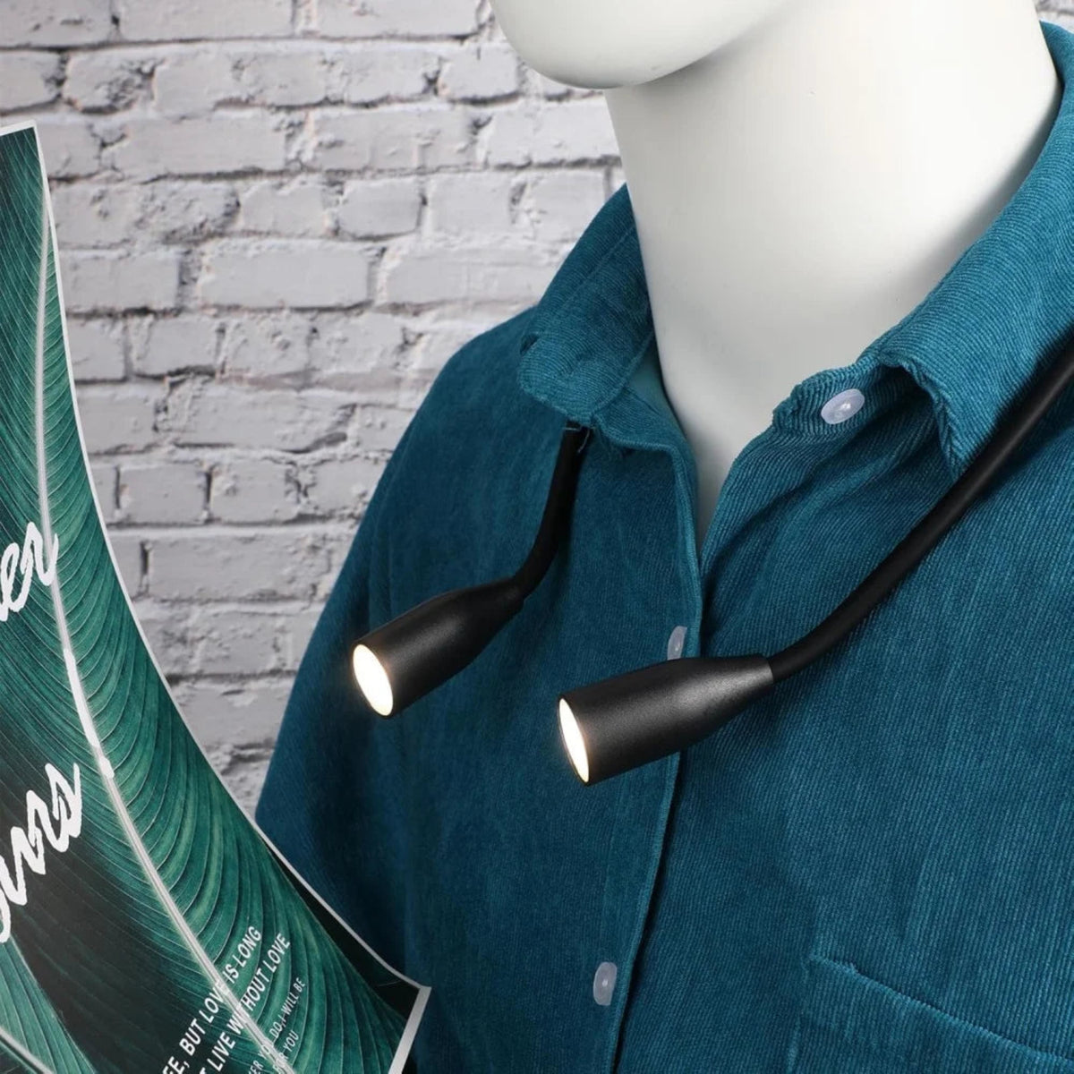 Close-up of the black neck reading light worn over a shirt and directed towards a book.